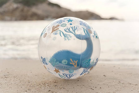 Doorzichtige strandbal van Little Dutch met een blauwe walvis in de strandbal ligt op het strand