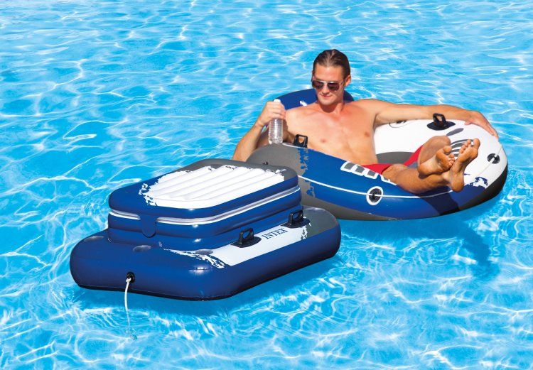 Laad afbeelding in galerijtoner, Een man drijft op het water op een opblaasband met daarnaast een wit met blauw en zwart opblaasbare drijvende Intex koelbox
