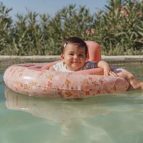 Een meisje drijft op het water in een Little Dutch Ocean Dreams Babyfloat 67 cm Roze