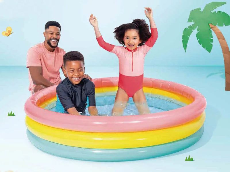 Laad afbeelding in galerijtoner, Twee kinderen spelen in een kleurrijk opblaasbaar kinderzwembad van Intex met roze, geel en groene ringen waar een man naast het bad zit
